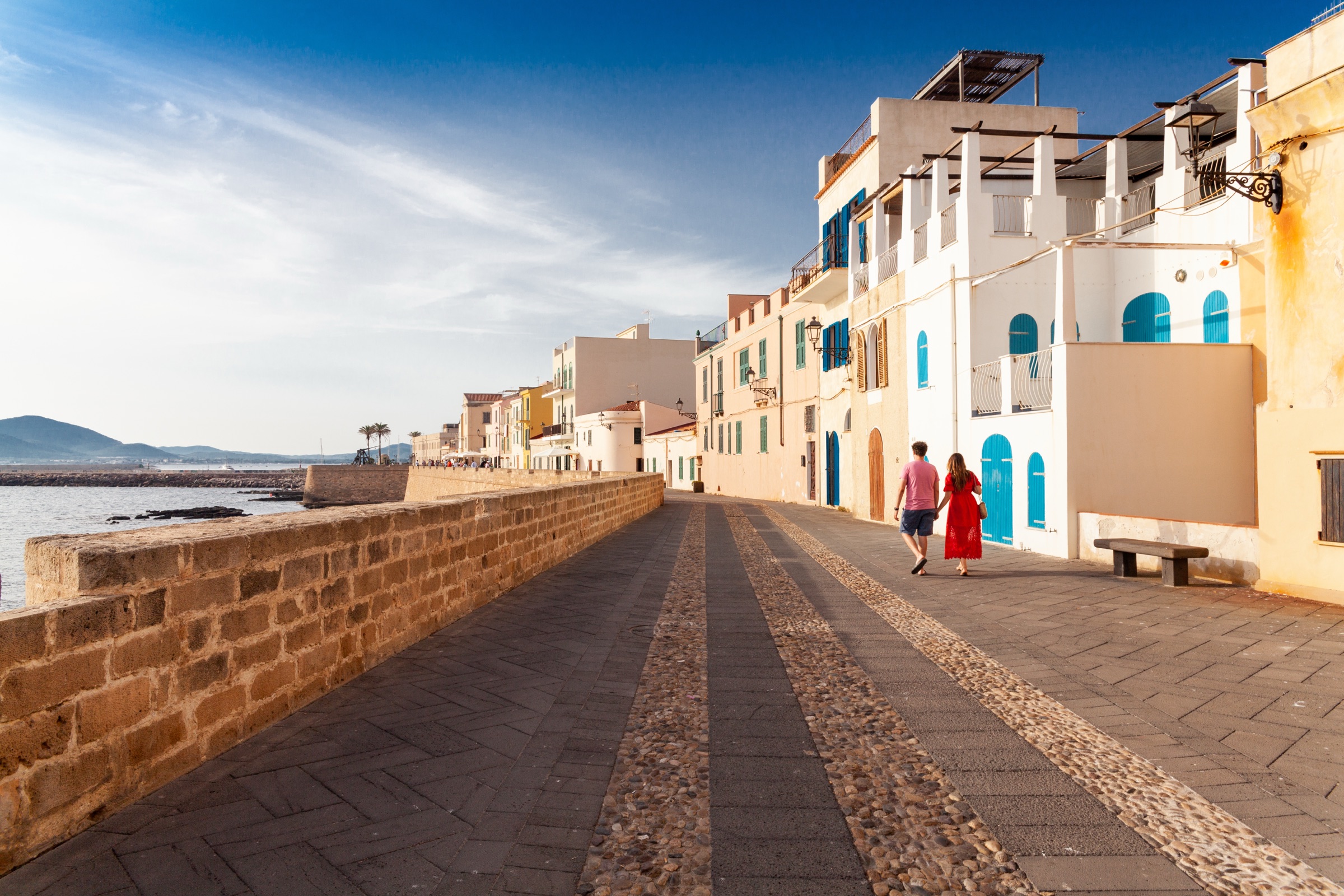Couple walking along the Alghero ramparts in golden light