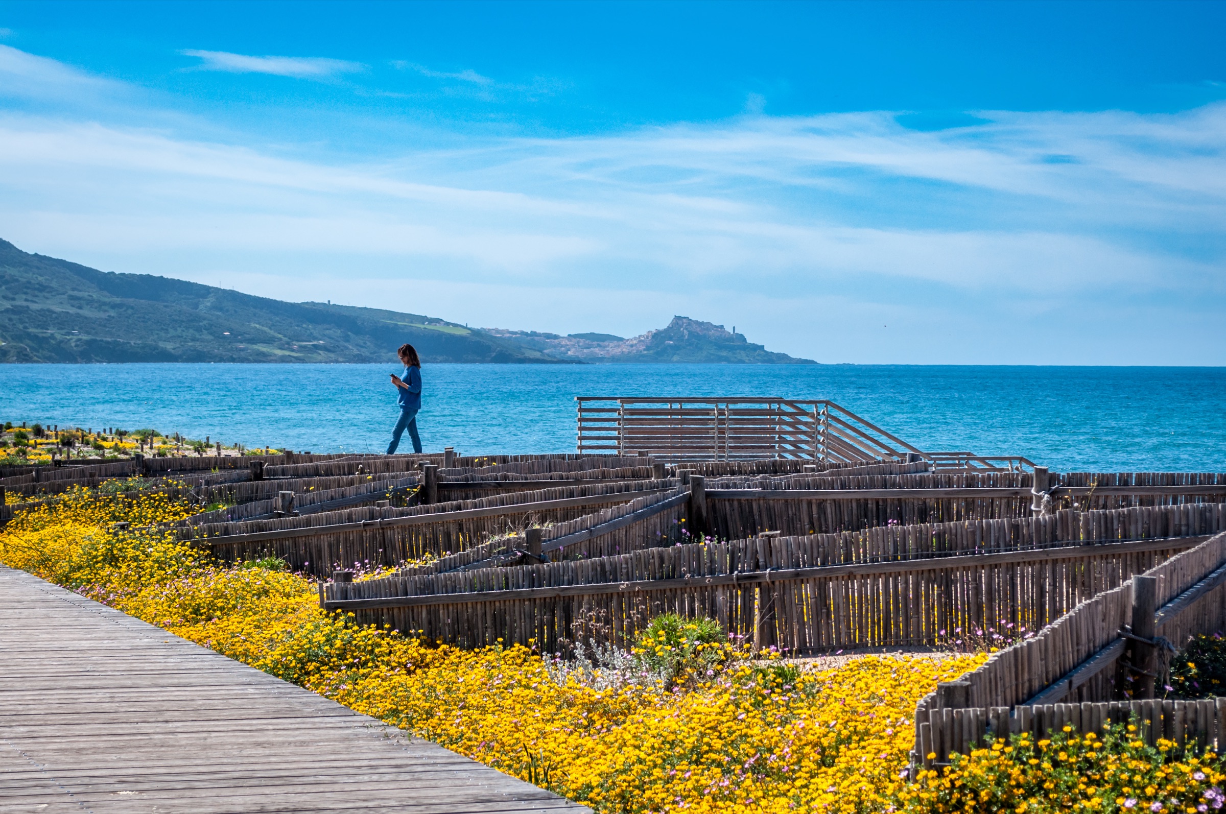 Boardwalk through dunes at San Pietro a Mare, with Castelsardo castle on the horizon