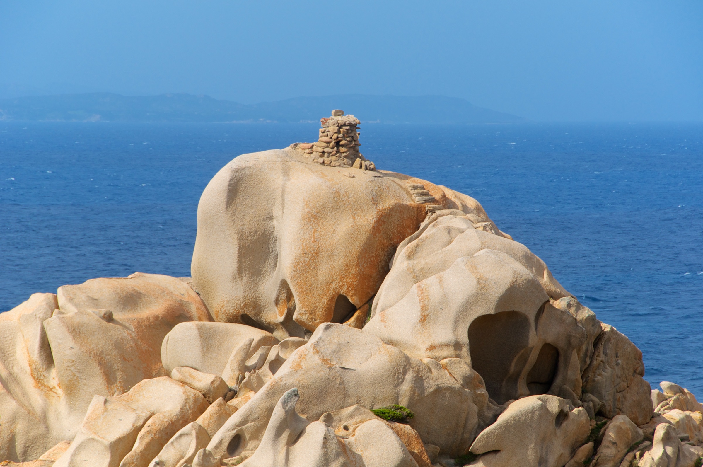 Wind-sculpted granite boulders at Capo Testa, with Corsica on the horizon
