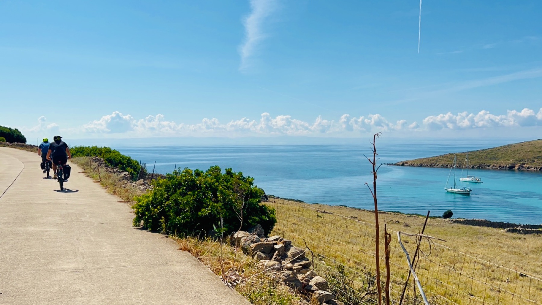 Cyclists riding the empty coast road of Asinara on rental eBikes