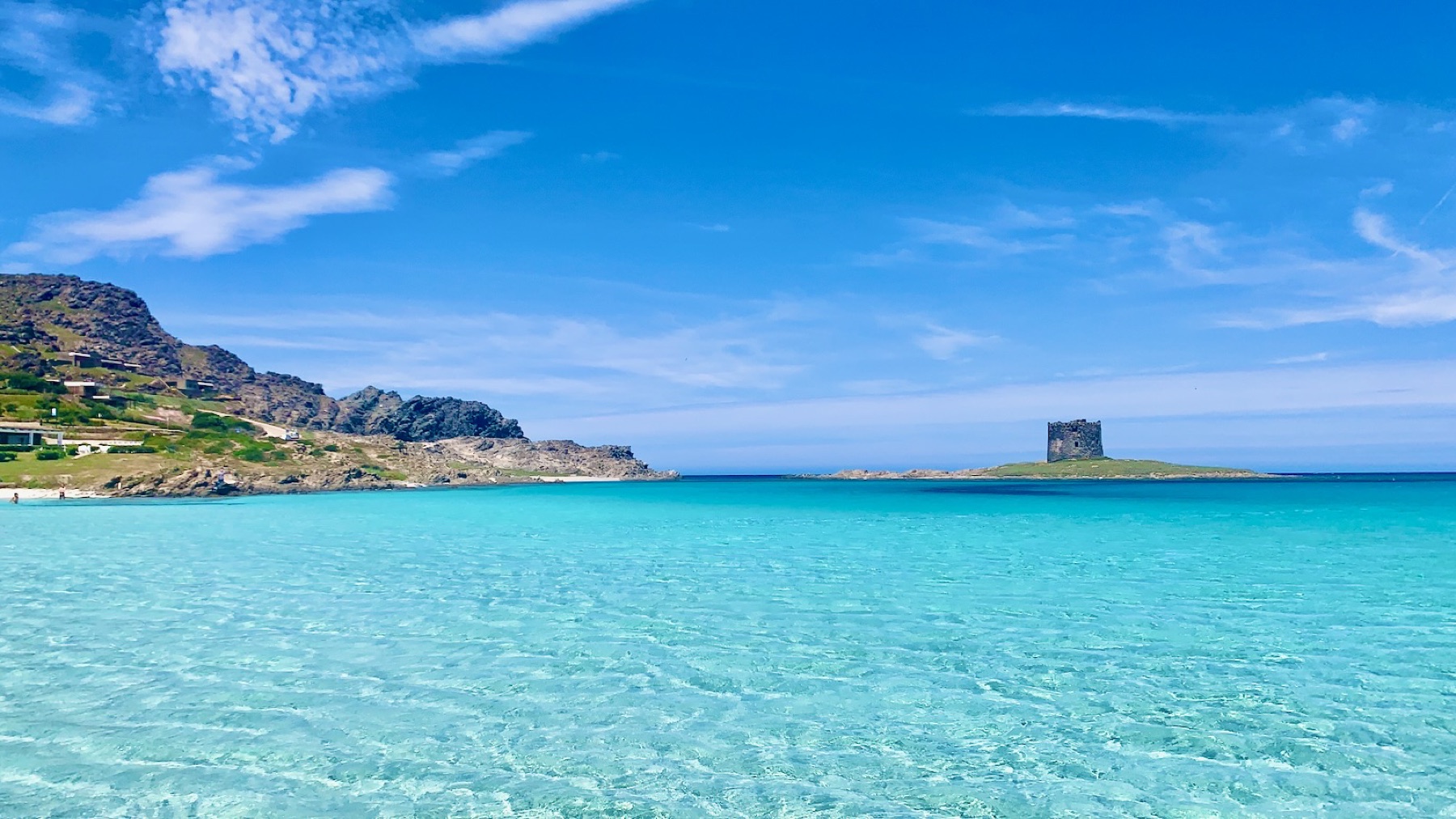 La Pelosa beach in shallow turquoise water, looking out to the Aragonese tower on Isola Piana