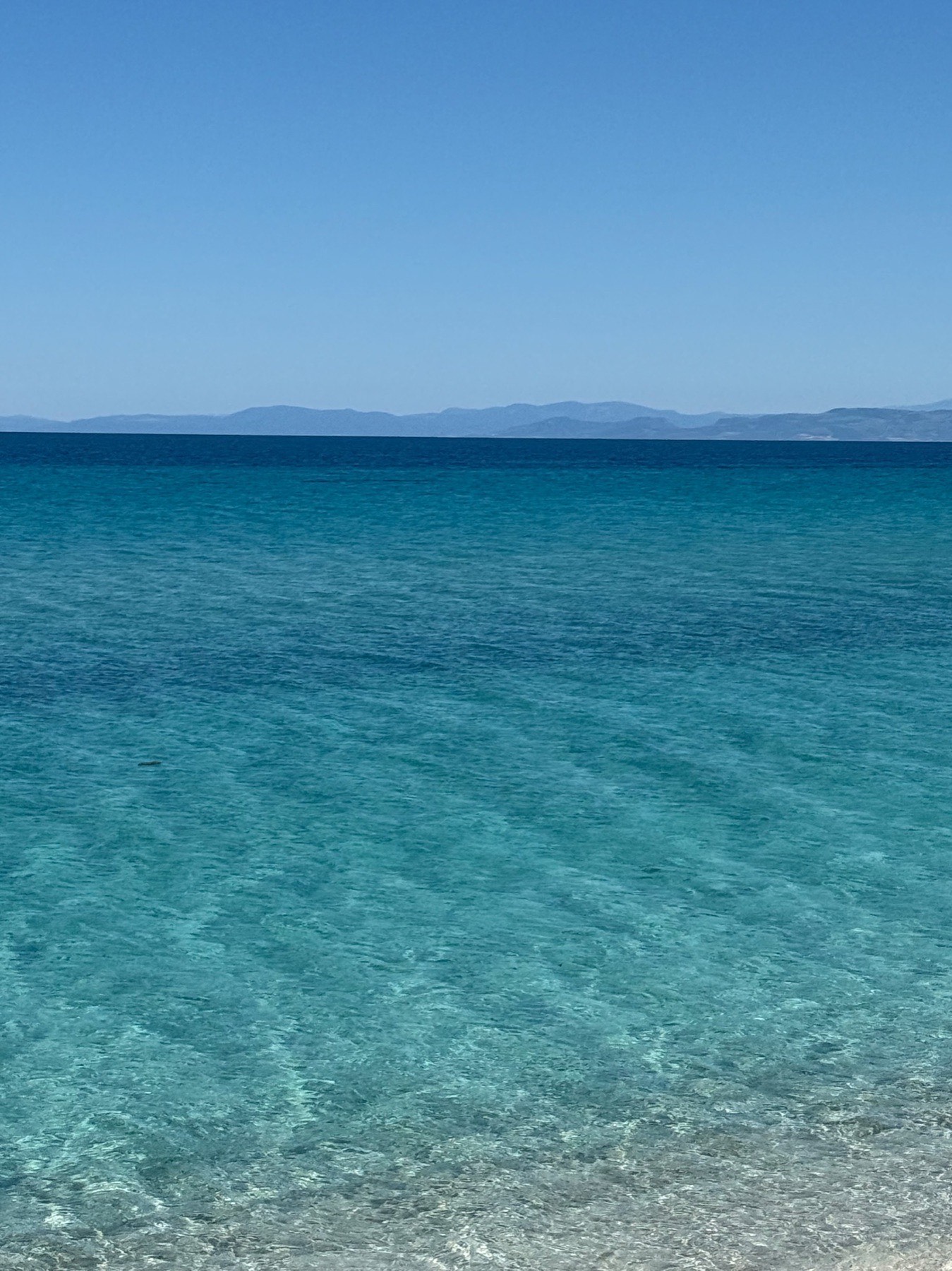 Calm water at Le Saline, with mountains on the horizon