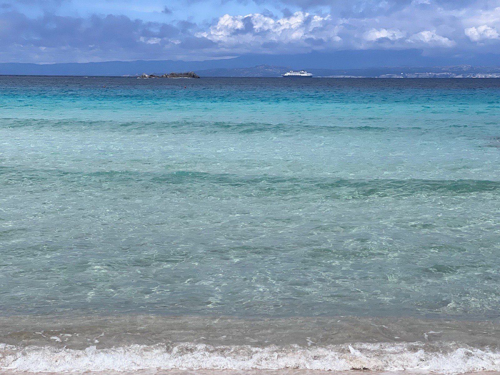 Wide view of Rena Bianca beach with bathers and the headland