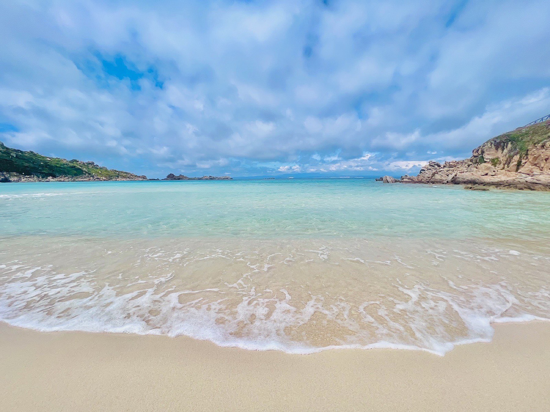 Shallow turquoise water lapping the sand at Rena Bianca beach, Santa Teresa di Gallura
