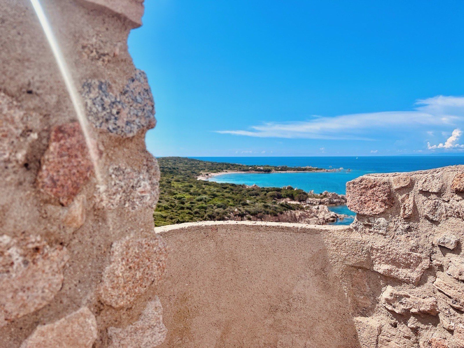 View of the Vignola Mare cove framed through the stones of the Spanish watchtower